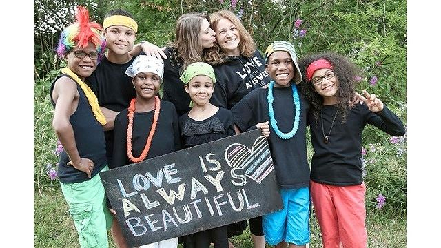 Gia đ&igrave;nh Hart cầm tấm biển ghi d&ograve;ng chữ