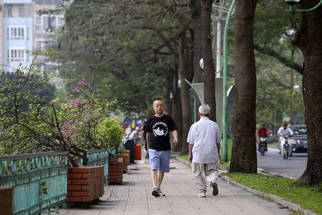 Nhiều người tản bộ tr&ecirc;n con đường nhiều c&acirc;y xanh b&ecirc;n hồ Tr&uacute;c Bạch.