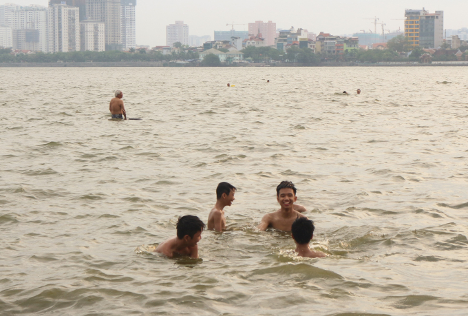 Rất nhiều người chọn c&aacute;ch ng&acirc;m m&igrave;nh dưới Hồ T&acirc;y để tắm m&aacute;t d&ugrave; đ&atilde; c&oacute; biển cảnh b&aacute;o nguy hiểm.
