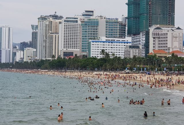 B&atilde;i biển ph&iacute;a đ&ocirc;ng đường Trần Ph&uacute;, TP Nha Trang với d&ograve;ng người tắm biển k&eacute;o d&agrave;i h&agrave;ng c&acirc;y số