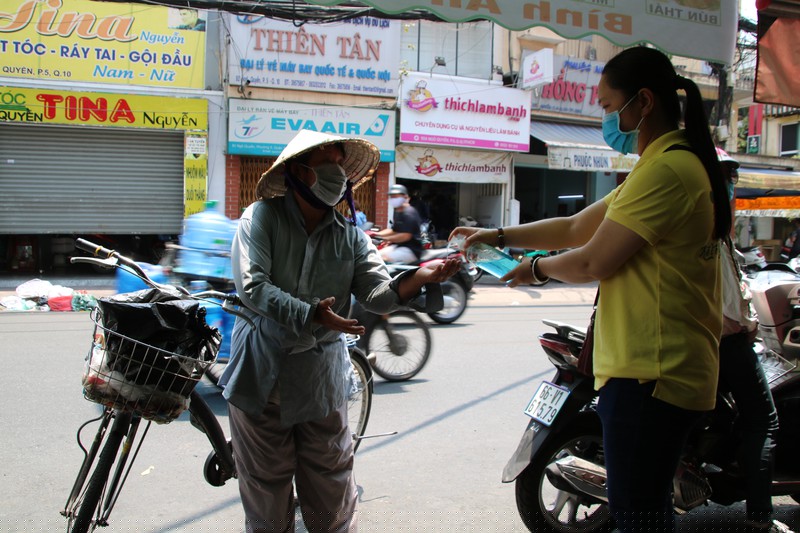 Chị Phương Thảo xịt nước rửa tay cho bà con trước khi trao cơm từ thiện 