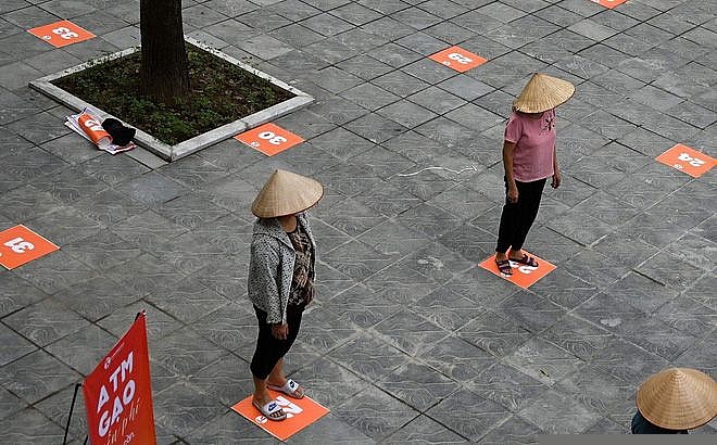 Người dân xếp hàng cách nhau 2 mét theo quy định để phòng chống dịch Covid-19 trước một địa điểm đặt ATM Gạo tại Hà Nội. (Nguồn: AFP)