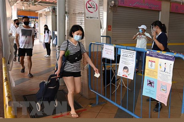 Người dân đeo khẩu trang và thực hiện giãn cách xã hội phòng lây nhiễm dịch COVID-19 tại một chợ ở Singapore. (Ảnh: AFP/TTXVN)