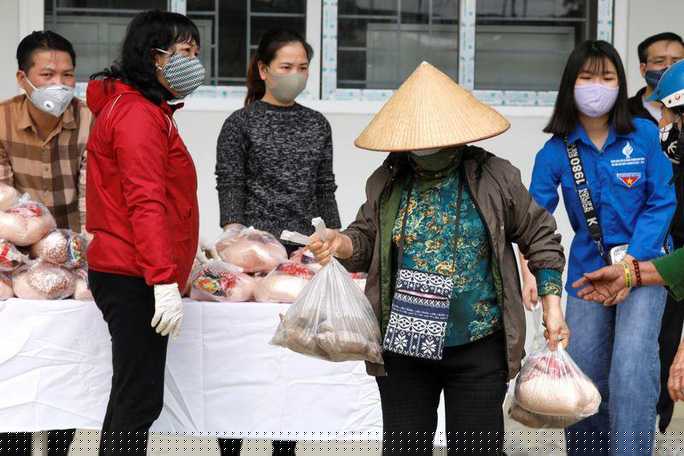 Một phụ nữ nhận thức ăn được hỗ trợ ở Hà Nội ngày 7-4. Ảnh: Reuters