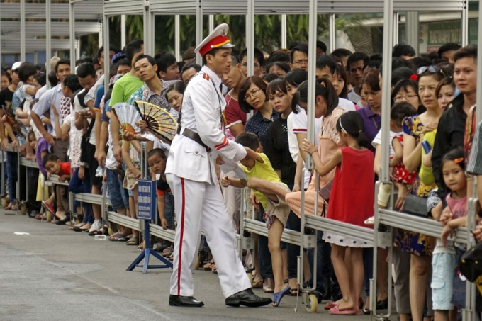 Một người l&iacute;nh cảnh vệ đưa ch&aacute;u b&eacute; ra khỏi d&ograve;ng người để ưu ti&ecirc;n l&ecirc;n trước