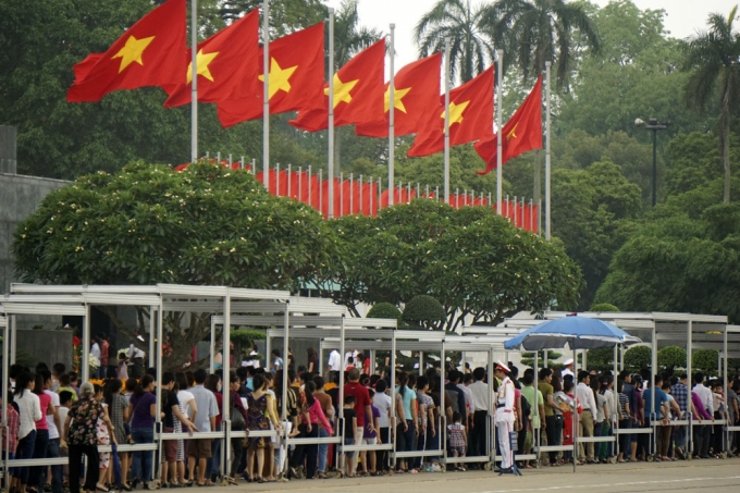 D&ograve;ng người chờ vao viếng B&aacute;c dưới h&agrave;ng cờ đỏ sao v&agrave;ng tung bay tr&ecirc;n kh&aacute;n đ&agrave;i