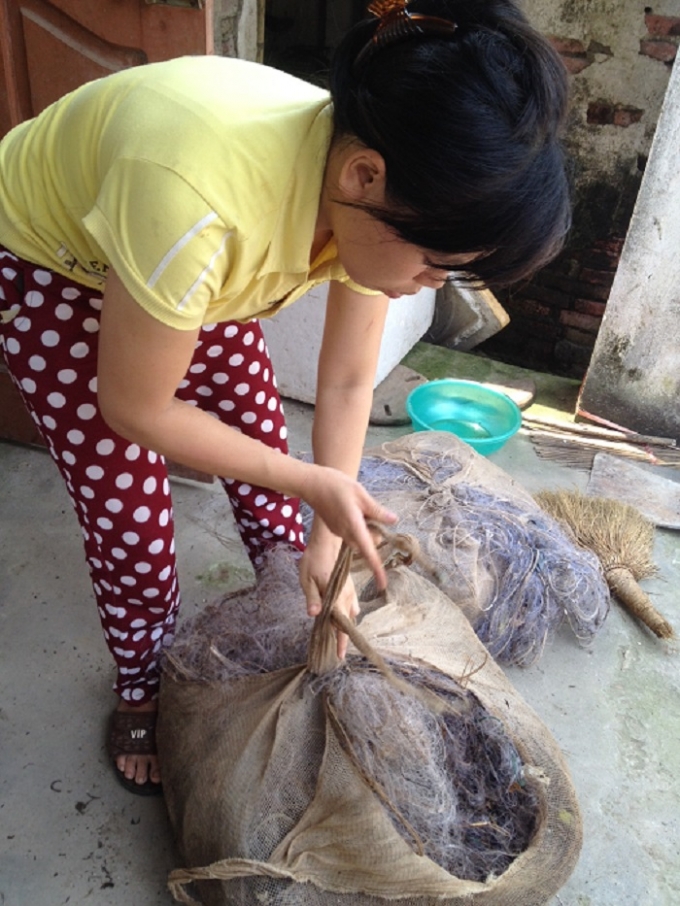 Chị Hằng, vợ anh Quang Anh đang buộc lại đống lưới d&iacute;nh đầy r&aacute;c va phải cọc v&acirc;y tr&ecirc;n biển bị r&aacute;ch bươm, vứt một chỗ từ mấy th&aacute;ng nay. Ảnh: Trung Du.&nbsp;