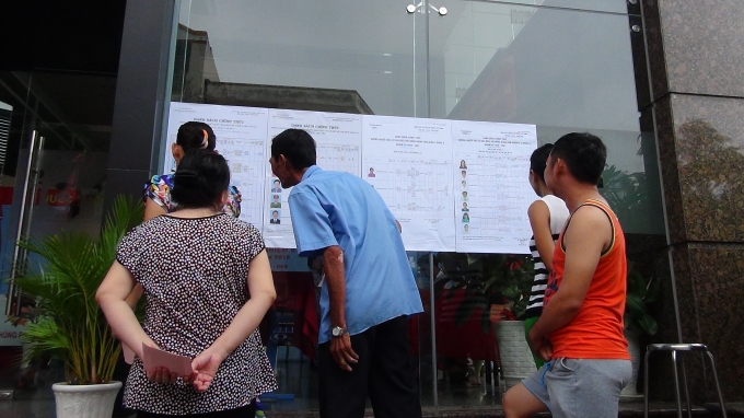 Cử tri phường 12, quận 4 chăm ch&uacute; nghi&ecirc;n cứu tiểu sử ứng vi&ecirc;n trước khi quyết định bầu.