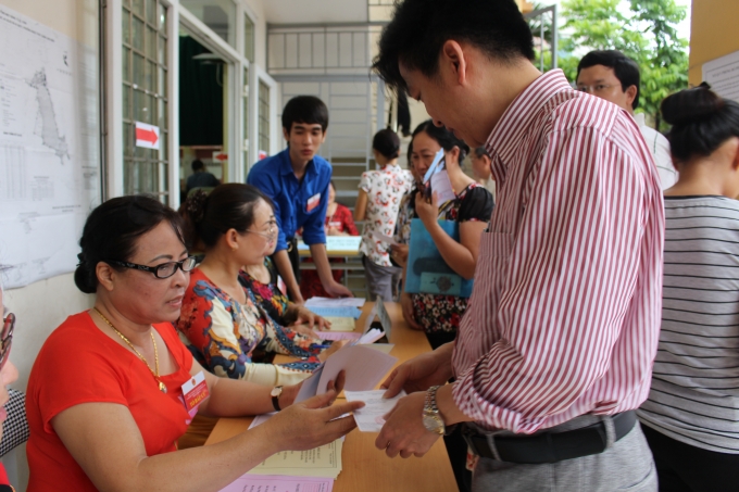 Tổ bầu cử hướng dẫn c&aacute;c cử tri th&ocirc;ng tin tr&ecirc;n l&aacute; phiếu bầu cử.