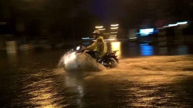 Người điều khiển xe gắn m&aacute;y cố gắng đi nhanh qua c&aacute;c đoạn đường bị ngập.