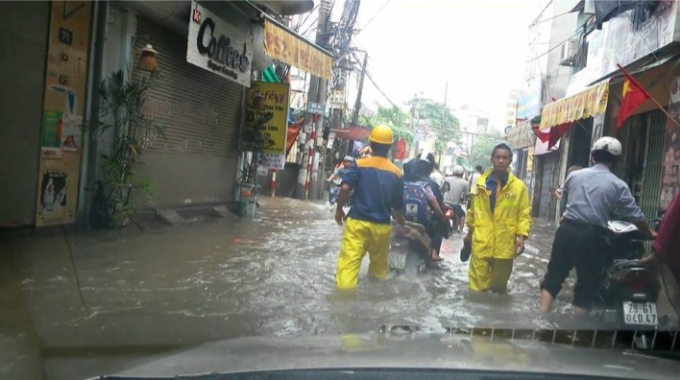 Những c&ocirc;ng nh&acirc;n Cty tho&aacute;t nước tại phố Triều Kh&uacute;c vừa l&agrave;m nhiệm vụ vừa hỗ trợ đẩy xe m&aacute;y cho người tham gia giao th&ocirc;ng bị chết m&aacute;y khi di chuyển qua đ&acirc;y. (Ảnh: Huy Trung)