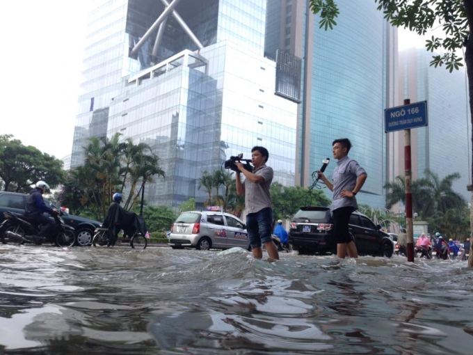 Kh&ocirc;ng chỉ c&oacute; n&ocirc;ng d&acirc;n phải xắn quần lội ruộng, ng&agrave;y 25/5, c&aacute;c ph&oacute;ng vi&ecirc;n tr&ecirc;n địa b&agrave;n H&agrave; Nội cũng xắn quần, lội đường t&aacute;c nghiệp. (Đường Trần Duy Hưng, H&agrave; Nội)