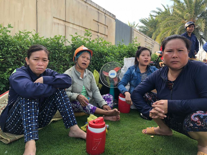 C&aacute;c c&ocirc;ng nh&acirc;n ngồi thẫn thờ sau vụ ch&aacute;y.