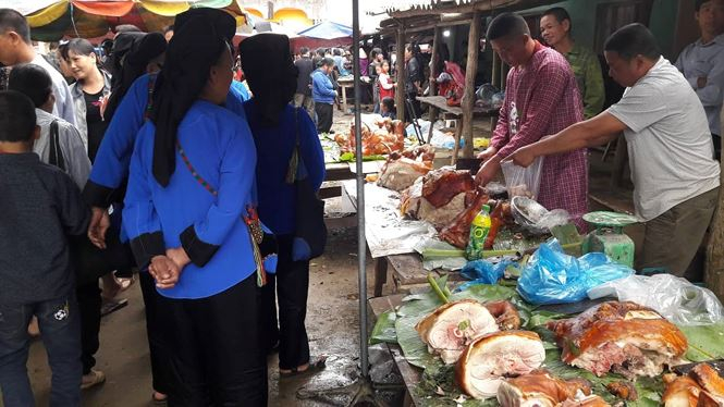 Người T&agrave;y- N&ugrave;ng vận quần &aacute;o d&acirc;n tộc đi mua thịt lợn quay về đ&atilde;i kh&aacute;ch. Ảnh: Duy Chiến.