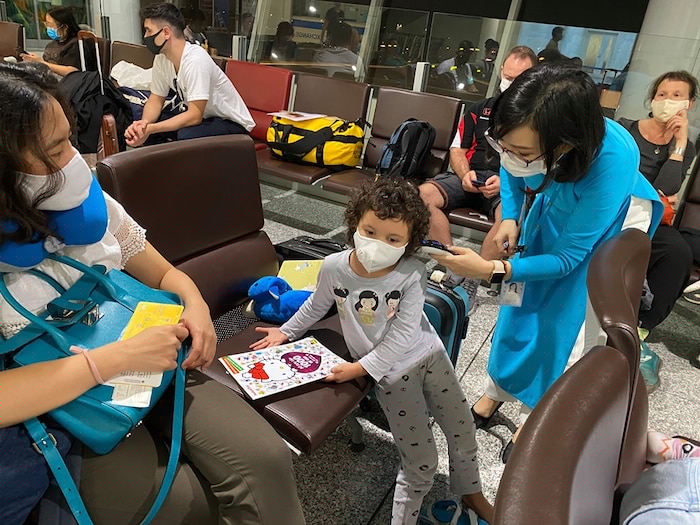 Nh&acirc;n vi&ecirc;n h&atilde;ng h&agrave;ng kh&ocirc;ng đang kiểm tra th&acirc;n nhiệt cho h&agrave;nh kh&aacute;ch.