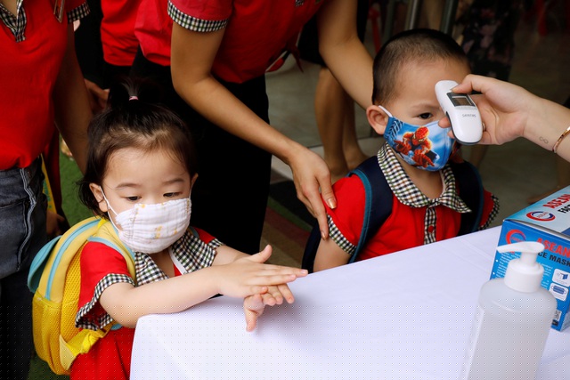 Các em nhỏ tại Hà Nội được đo nhiệt độ và hướng dẫn rửa tay trong ngày đầu tiên trở lại trường học sau thời gian cách ly xã hội. (Ảnh: Reuters/Kham)
