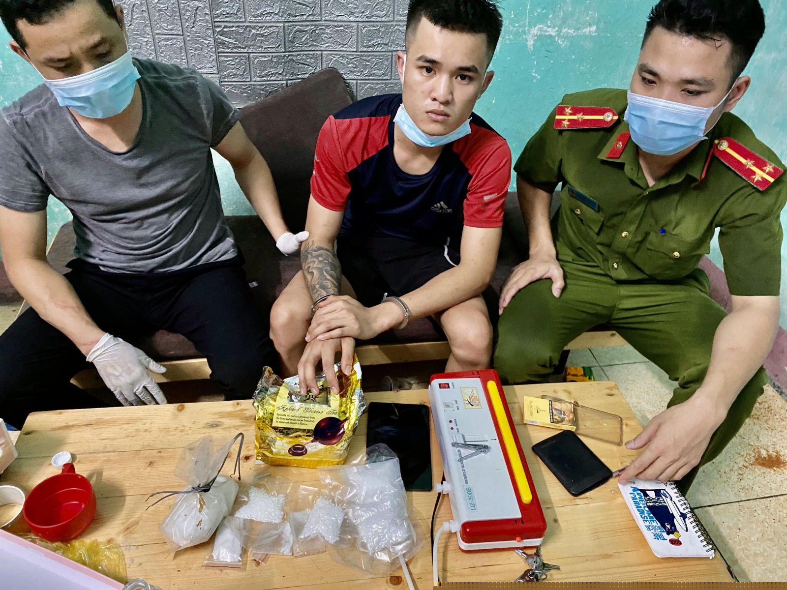 Đối tượng Đoàn Văn Nam (áo đỏ) và tang vật thu được   