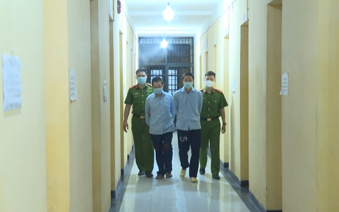 Lực lượng Công an dẫn giải hai đối tượng cầm đầu sàn tiền ảo. Ảnh: Báo Nhân Dân