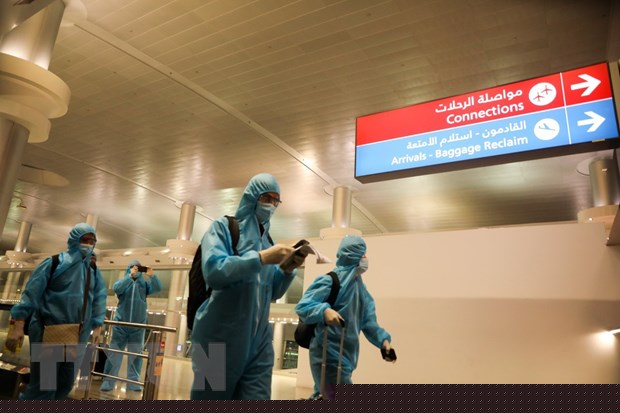 Đội tuyển Việt Nam di chuyển tại sân bay trong trang phục bảo hộ. (Ảnh: Hoàng Linh/TTXVN)