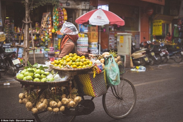 Chị b&aacute;n hoa quả d&ugrave;ng cả t&uacute;i nilon đội đầu khi trời đổ mưa lất phất.