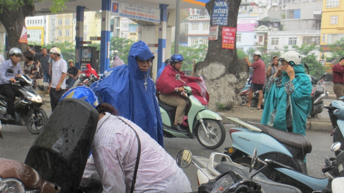 Mặc d&ugrave; trời mưa to, nhưng hầu hết c&aacute;c bậc phụ huynh đều sẵn s&agrave;ng đội mưa để c&ugrave;ng con m&igrave;nh trải qua m&ocirc;n thi To&aacute;n. (Ảnh: Thu Hường)