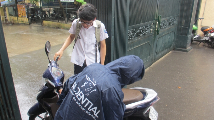 Một bạn do qu&ecirc;n mang m&aacute;y t&iacute;nh n&ecirc;n phải nhờ bố mang đến điểm thi khi trời mưa to. (Ảnh: Thu Hường)