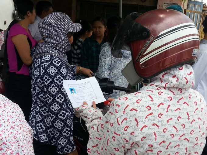 Phụ huynh đang xem lại th&ocirc;ng tin tr&ecirc;n thẻ dự thi cho con m&igrave;nh.