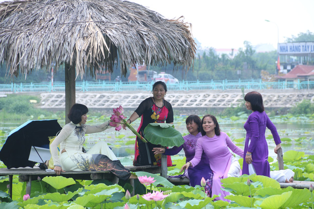 Kh&ocirc;ng chỉ c&oacute; c&aacute;c bạn trẻ th&iacute;ch chụp ảnh c&ugrave;ng hoa sen, nhiều phụ nữ trung tuổi cũng ra hồ tạo d&aacute;ng với hoa sen b&ecirc;n &aacute;o d&agrave;i truyền thống để ghi lại những kỷ niệm.