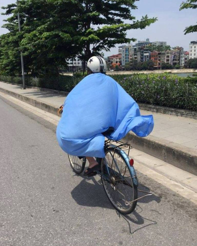 Một người phụ nữ phải ch&ugrave;m cả chiếc khăn cho&agrave;ng mỏng để che nắng. (Ảnh: Đ.N)