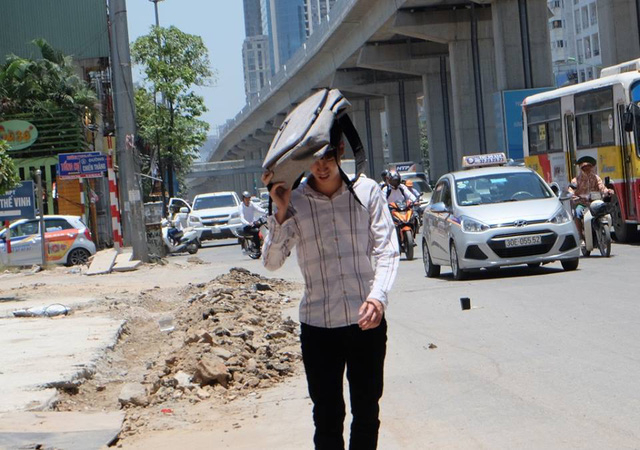 Một thanh ni&ecirc;n phải d&ugrave;ng ba l&ocirc; che l&ecirc;n đầu tr&aacute;nh nắng