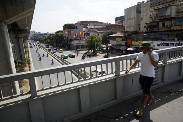 Một người đi bộ k&eacute;o cao cổ &aacute;o che nắng khi ra ngo&agrave;i dưới nắng gay gắt.