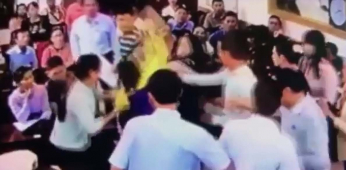 Trần Thị Phi Yến (&aacute;o kho&aacute;c v&agrave;ng) đang h&agrave;nh hung b&agrave; Mỹ Anh bằng t&uacute;i x&aacute;ch cầm tr&ecirc;n tay tại phi&ecirc;n đấu gi&aacute;. (ảnh cắt từ clip).