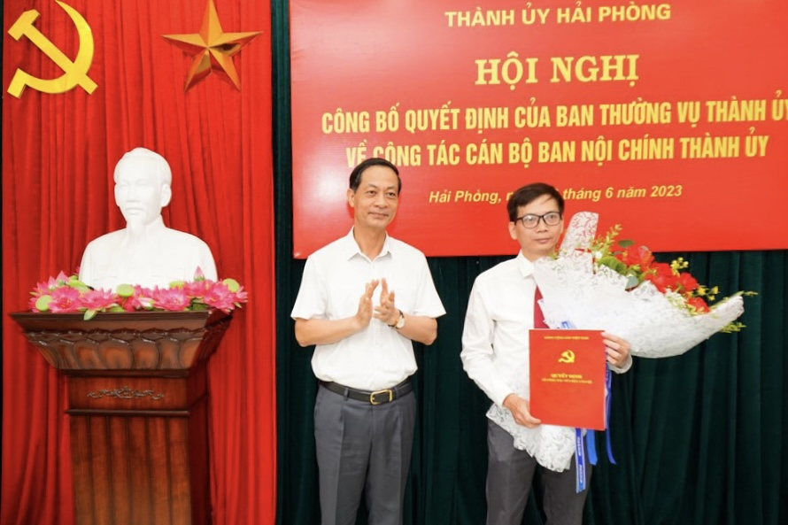Phó Bí thư Thường trực Thành ủy Hải Phòng trao Quyết định và tặng hoa cho ông Trần Thanh Minh.