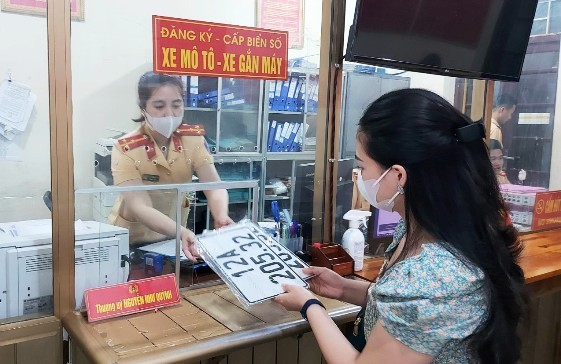 Cán bộ CSGT giao biển số xe cho người dân.