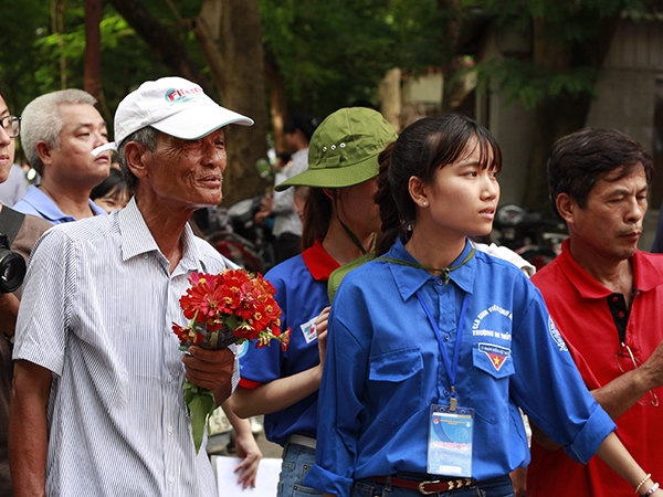 &Ocirc;ng Tạ Minh Đức (H&agrave; Đ&ocirc;ng) cầm b&oacute; hoa nhỏ v&agrave; hướng đ&ocirc;i mắt về ph&iacute;a cổng trường chờ ch&aacute;u g&aacute;i để tặng b&oacute; hoa nhỏ.&nbsp;