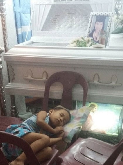 Cậu b&eacute; xếp ghế nằm cạnh quan t&agrave;i mẹ trước ng&agrave;y đưa tang.Ảnh letribunaldunet.