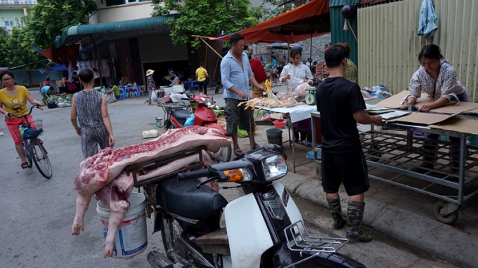 Một đ&ocirc;i vợ chồng vừa chở thịt lợn đến khu chợ c&oacute;c nằm trong khu đ&ocirc; thị Xa La (quận H&agrave; Đ&ocirc;ng) bằng xe m&aacute;y.