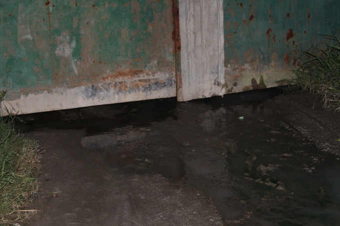 Nước từ xưởng dệt chảy ra đường qua khe cửa.