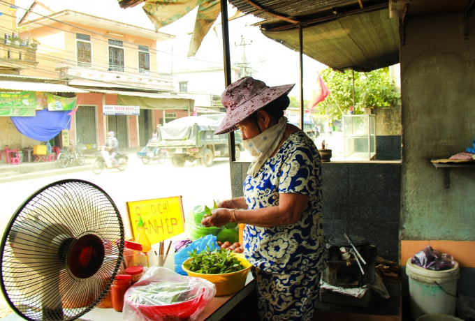 Một người d&acirc;n bu&ocirc;n b&aacute;n gần đường phải bịt khăn để tr&aacute;nh bụi. Qu&aacute;n ăn th&igrave; ế ẩm v&igrave; bụi qu&aacute; nhiều, kh&ocirc;ng ai d&aacute;m ăn.