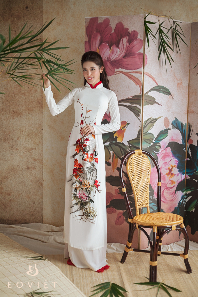 Thiết kế &aacute;o d&agrave;i trắng cổ cao nhưng vẫn kh&ocirc;ng hề cứng v&agrave; đơn điệu bởi họa tiết chim c&ocirc;ng v&agrave; hoa nổi bật tr&ecirc;n nền trắng.