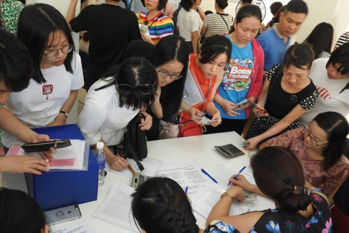 Phụ huynh chen ch&acirc;n nộp hồ sơ nhập học cho con v&agrave;o lớp 10. Ảnh: Đ&igrave;nh Tuệ