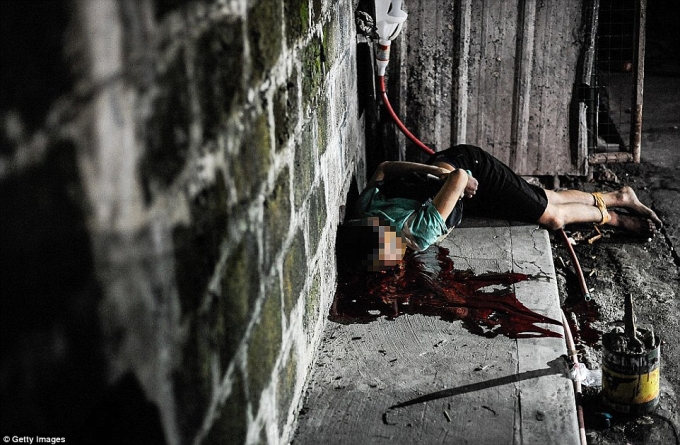 Cảnh s&aacute;t chụp ảnh 1 nạn nh&acirc;n t&igrave;nh nghi l&agrave; tội phạm ma t&uacute;y bị bắn chết trong tư thế 2 ch&acirc;n tay bị ch&oacute;i v&agrave; quấn băng k&iacute;n đầu tr&ecirc;n đường phố Manila. (Ảnh: Daily Mail)