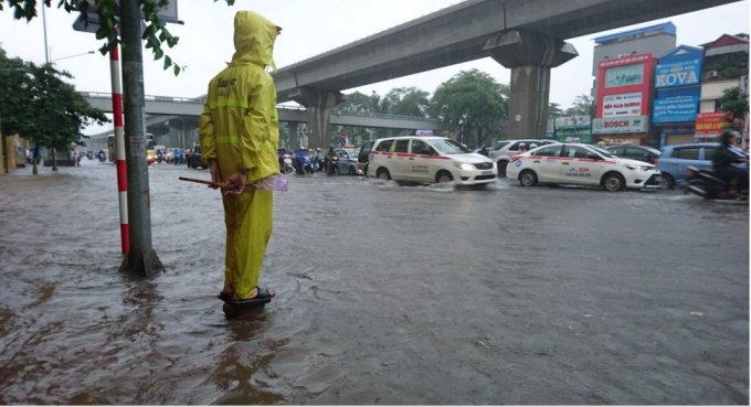 C&ocirc;ng nh&acirc;n tho&aacute;t nước đứng cảnh b&aacute;o điểm ngập s&acirc;u cho người tham gia giao th&ocirc;ng.