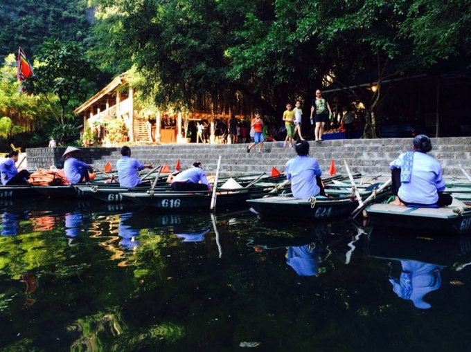 Những người ch&egrave;o thuyền ngồi tr&ecirc;n bờ đợi kh&aacute;ch du lịch.
