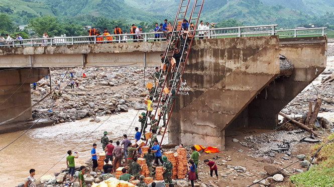 Cầu bị lũ chặt đứt, thanh ni&ecirc;n bắc thang vận chuyển gạo nước v&agrave;o v&ugrave;ng bị c&ocirc; lập.