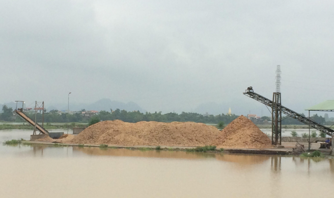 B&atilde;i tập kết dăm gỗ lấn chiếm ra s&ocirc;ng Ho&agrave;ng Long g&acirc;y ảnh hưởng đến d&ograve;ng chảy. Ảnh: Nguyệt Chi