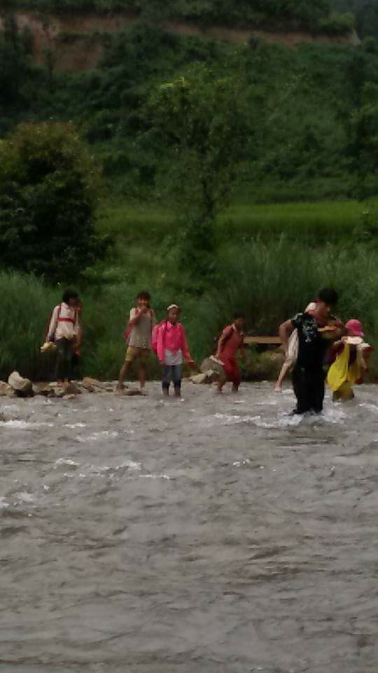 Thầy gi&aacute;o c&otilde;ng học tr&ograve; nhỏ vượt suối.