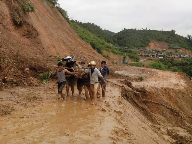 Thầy c&ocirc; v&aacute;c xe qua đường b&ugrave;n lầy lội.