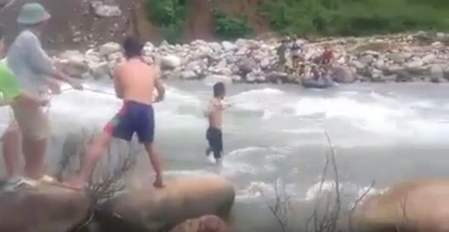 C&aacute;c thầy gi&aacute;o d&ugrave;ng d&acirc;y k&eacute;o v&agrave; b&aacute;nh xe lốp vượt suối dữ. (Ảnh cắt từ clip)