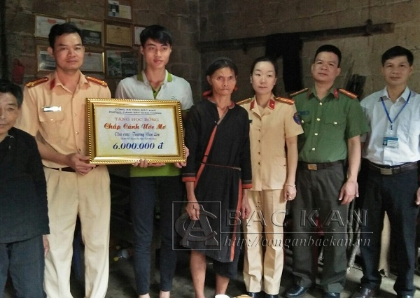 Đại diện l&atilde;nh đạo ph&ograve;ng CSGT v&agrave; C&ocirc;ng an huyện P&aacute;c Nặm trao qu&agrave; cho em Trương Văn L&ecirc;n (Ảnh: Conganbackan.vn).